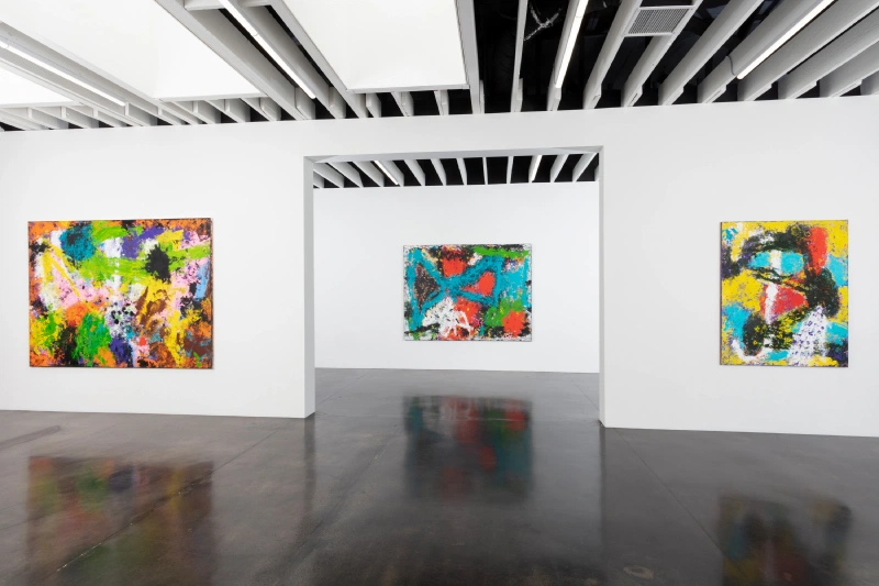 Three colorful abstract mixed-media works displayed across adjoining gallery rooms.