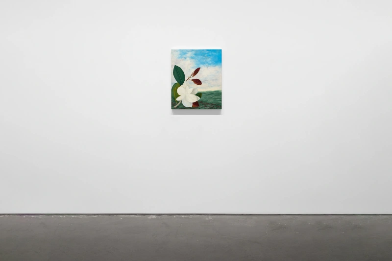 A small floral painting with white blossoms displayed alone on a wide white gallery wall.