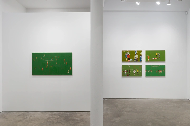 Green soccer-themed paintings displayed across adjoining white gallery walls.
