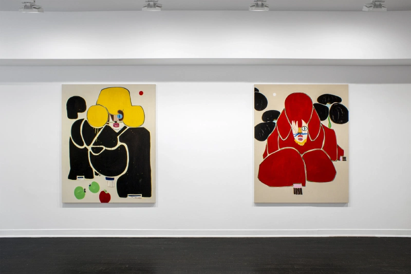 Two stylized poodle paintings, one yellow and one red, displayed side by side on a white wall.